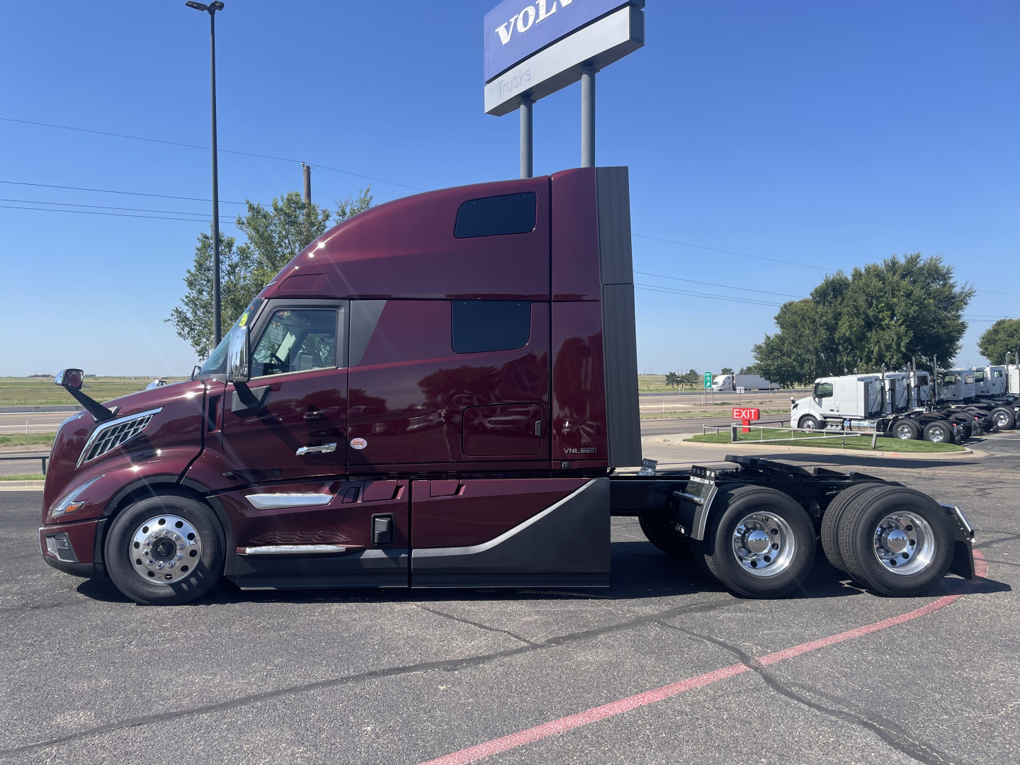 Volvo VNL64T860 sleeper cab tractor side view showing maroon paint, aerodynamic side fairings, dual rear axle, and large fuel tanks.