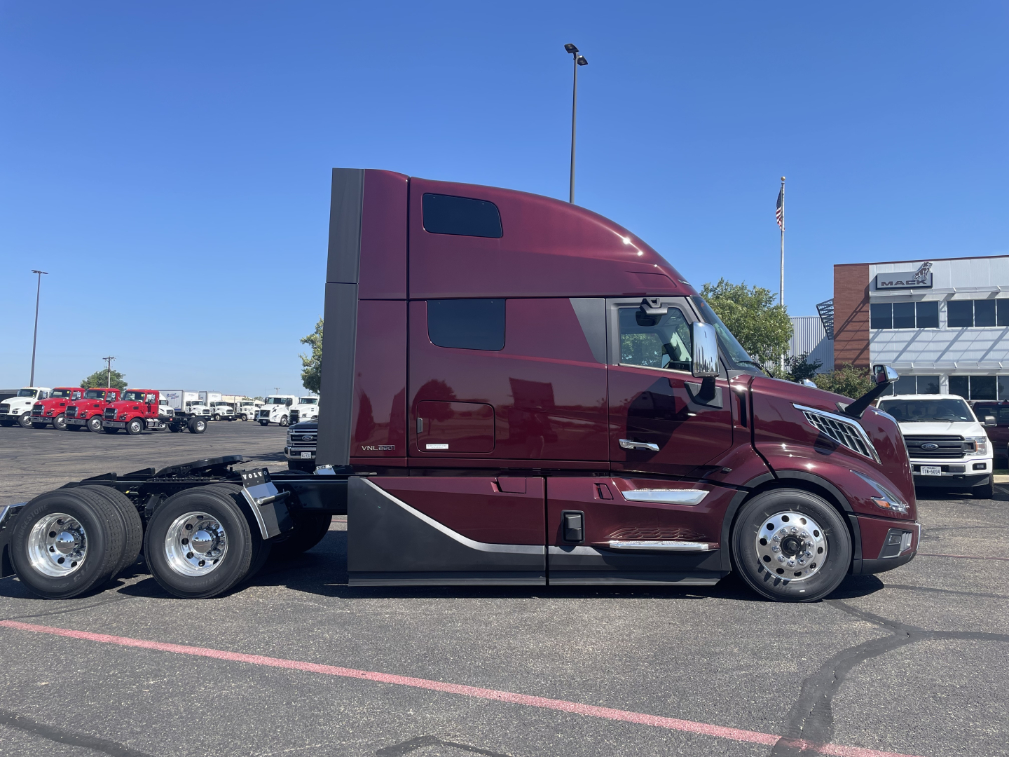 Volvo VNL64T860 tractor in burgundy showing side profile with sleeper cab, three rear axles, and chrome wheels.