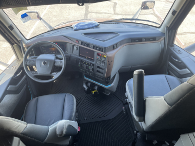 Volvo VNL64T860 cab interior showing steering wheel, dashboard, center console, and driver seat with floor mat.