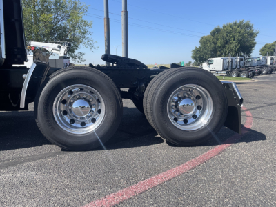 Volvo VNL64T860 tractor dual rear wheels showing chrome rims and black frame with various trucks in background.
