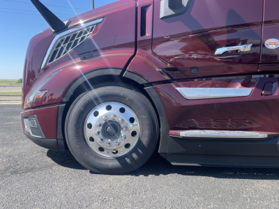 Volvo VNL64T860 truck front quarter showing front wheel, maroon color, cab side mirrors, and chrome accents.