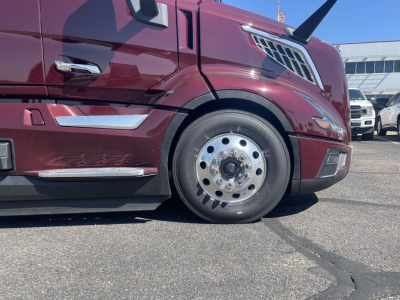 Volvo VNL64T860 front wheel and fender view showing chrome trim, maroon body, and steel wheel with hub cap.