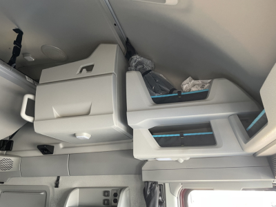 Interior cab area of a 2026 Volvo VNL truck showing storage cabinet, seating area, and overhead console with light gray and blue trim.