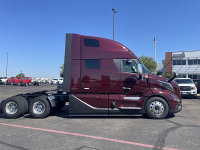 Volvo VNL64T860 tractor in burgundy showing side profile with sleeper cab, three rear axles, and chrome wheels.
