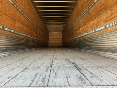 Trailer interior showing empty dry van cargo space with wooden walls and steel floor.