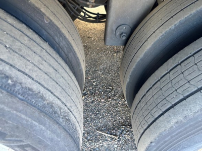 Trailer rear view showing dual rear axles with worn tires and wear bands on diameter, wheel wells, and undercarriage components visible.