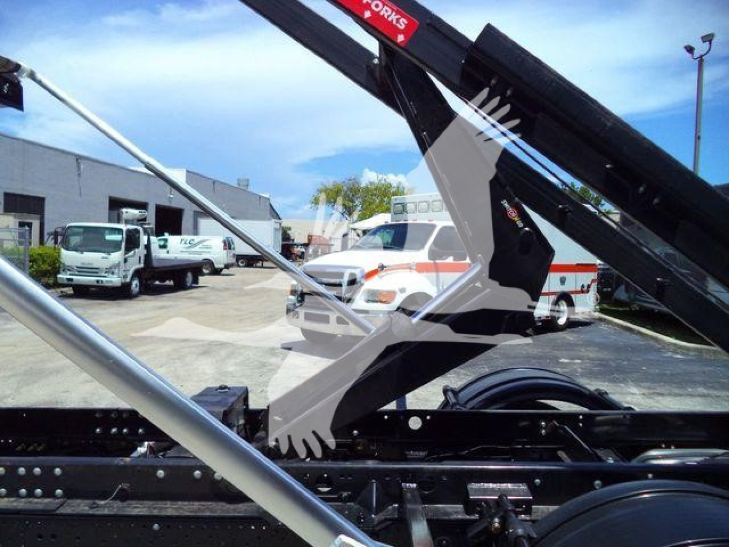 Isuzu NRR roll-off truck chassis with hydraulic arm and cables visible; stock number GASNRR14SNG2.