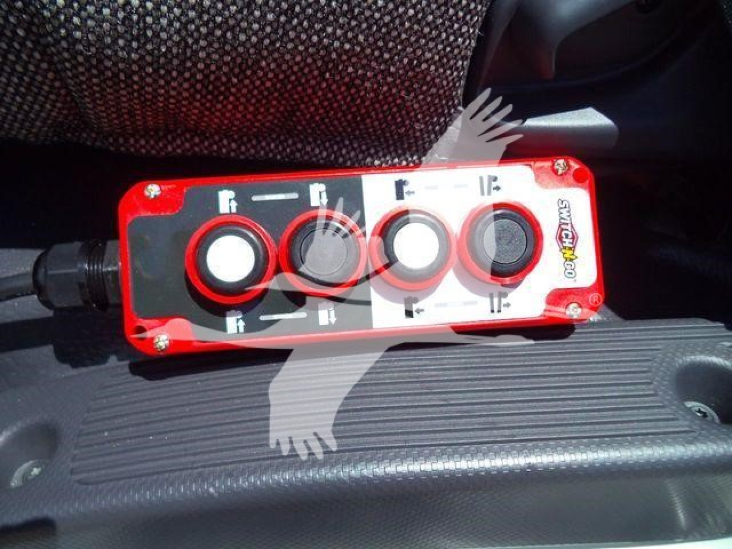 Red control panel with four circular knobs labeled with white icons on a truck interior surface.
