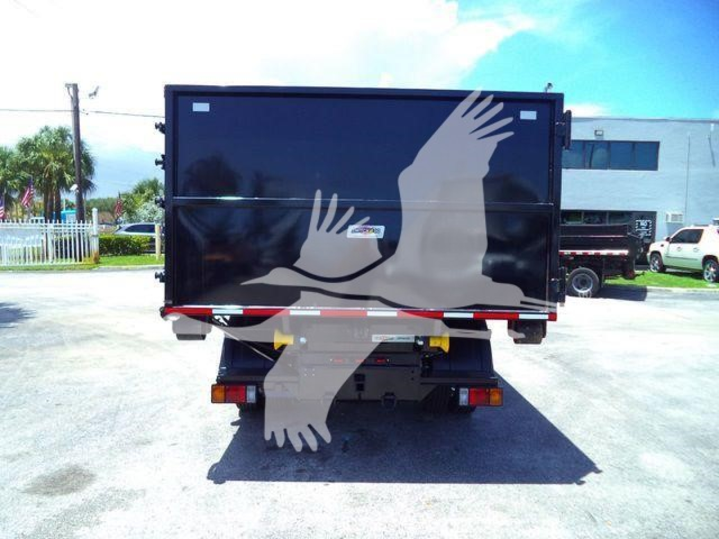 Isuzu NPRR roll-off truck rear view showing graphic of flying birds on black tailgate and rear lighting.