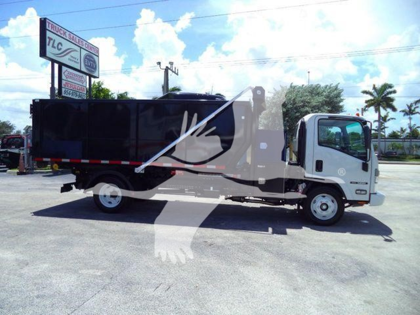 Isuzu NPRR roll-off truck in a dealership lot with a black dump body, side view showing cab and cargo area, stock number GASNRR14SNG2.