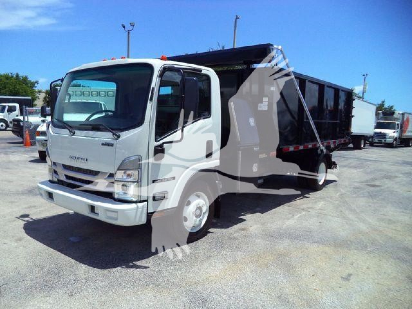 Isuzu NPR/NRR roll-off truck in a lot, white cab with black dump body, side view, stock yard background.