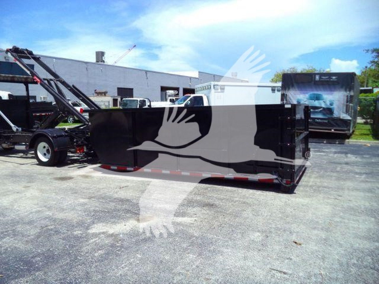 Isuzu NRR roll-off truck with a black/gray dump bed trailer. Side shows no legible labels; background shows a service yard.