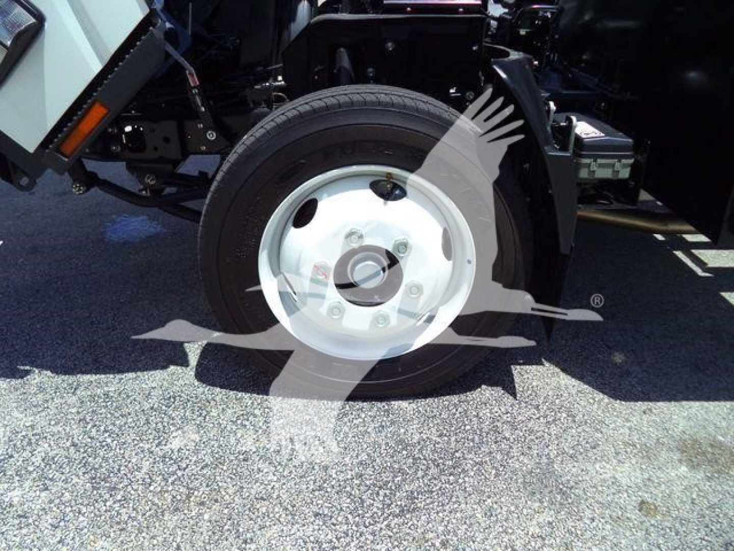 Isuzu NRR wheel and front suspension visible with tire and white hubcap in side view.