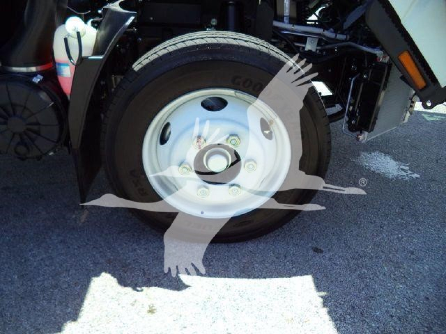 Isuzu NPRR rollover truck wheel and front suspension view showing white steel wheel and tire, part of a new 2024 Isuzu NRR rolloff truck.