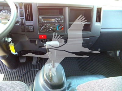 Dashboard and center console of a 2024 Isuzu NPRR rolloff truck interior with gear selector visible and various controls.