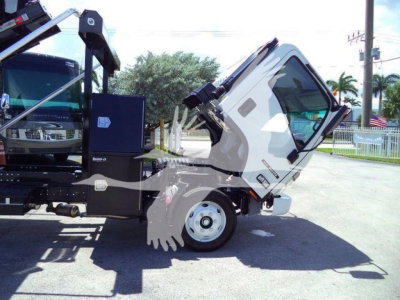 Isuzu NPR/RR new roll-off truck cab and chassis tilted forward showing cab interior, front wheel, and hydraulic components.