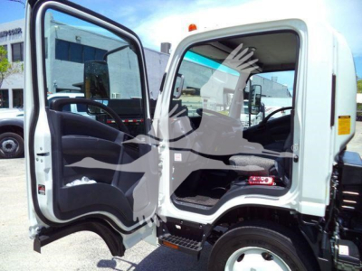 Isuzu NPR/NRR cab open showing interior including steering wheel and seat; partial view of exterior; white cab with black pedals and steps.