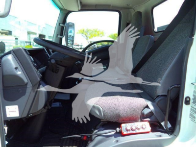 Isuzu NPRR cab interior with driver's seat and dashboard visible, including steering wheel and control panel; logo and some equipment mounted near seat.