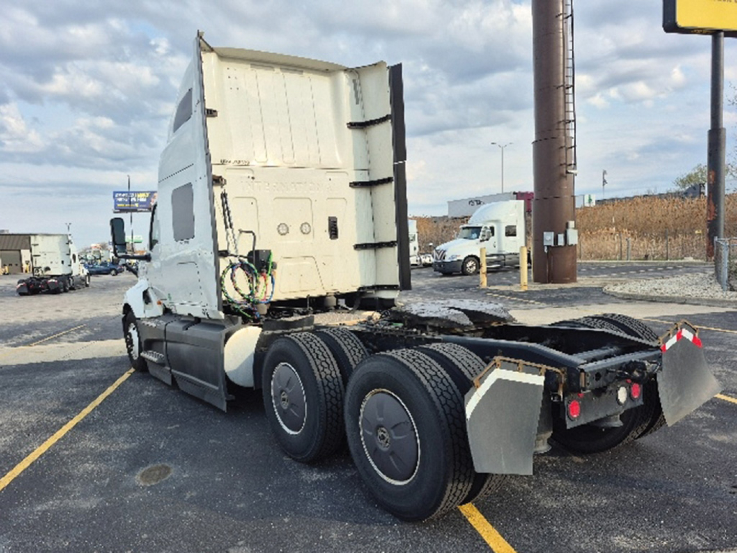 International LT625 truck tractor rear view showing fifth wheel and dual rear axles with mud flaps and tubing; cab is white with sleeper area visible.