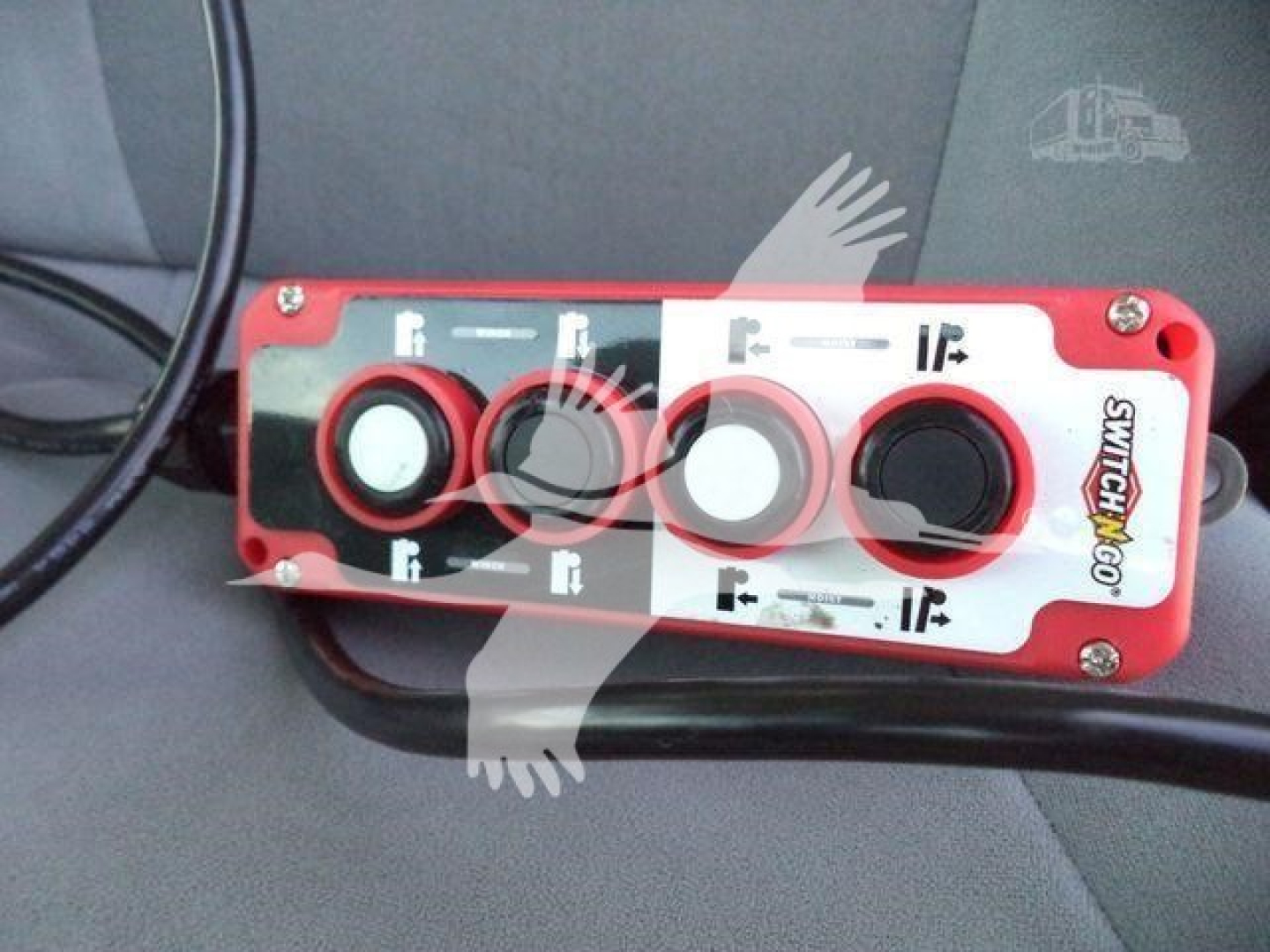 Isuzu NPR/Rolloff truck control panel with red housing and four circular buttons; labeled switches with white and black markings.