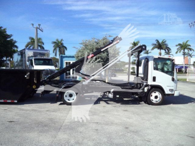 Isuzu NPR/NRR truck with rollback wreckers showing a hydraulic tow boom and flatbed in a dealership lot.