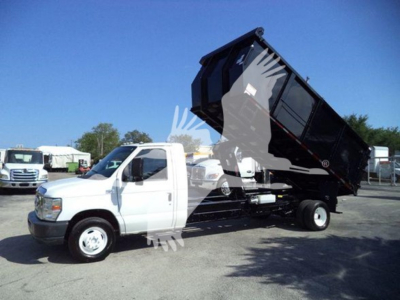 Ford E450 dump truck with raised dump bed showing side view of cab and hydraulic bed in serviceable condition.