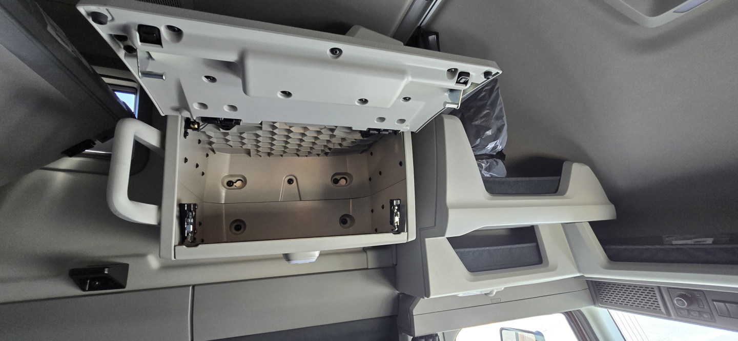 Volvo VNL truck interior showing overhead glovebox/console area with empty open storage compartment and surrounding dashboard components.