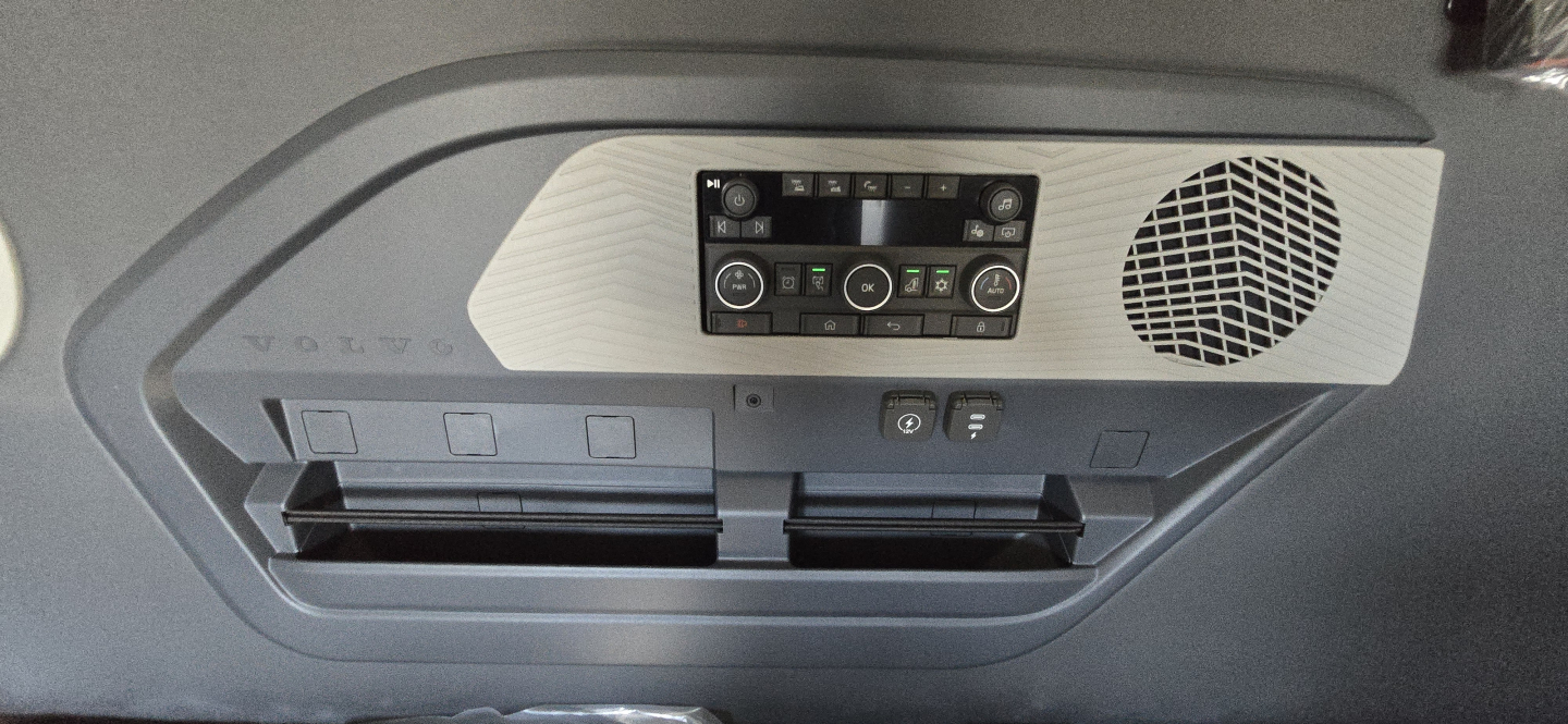 Volvo interior overhead console with climate controls and speaker grill, multiple storage slots visible.
