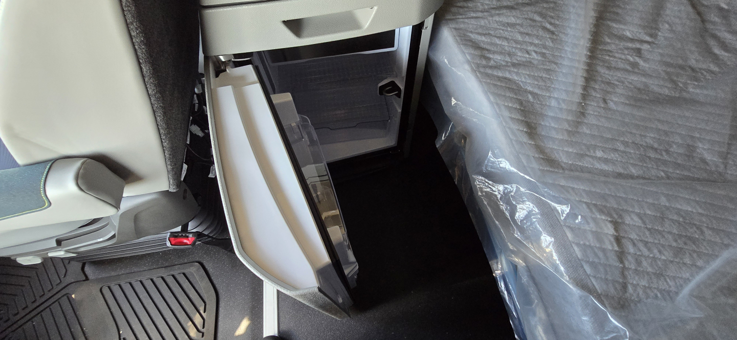 Volvo VNL64T860 truck interior showing open center console storage and passenger-side footwell with protective plastic cover.