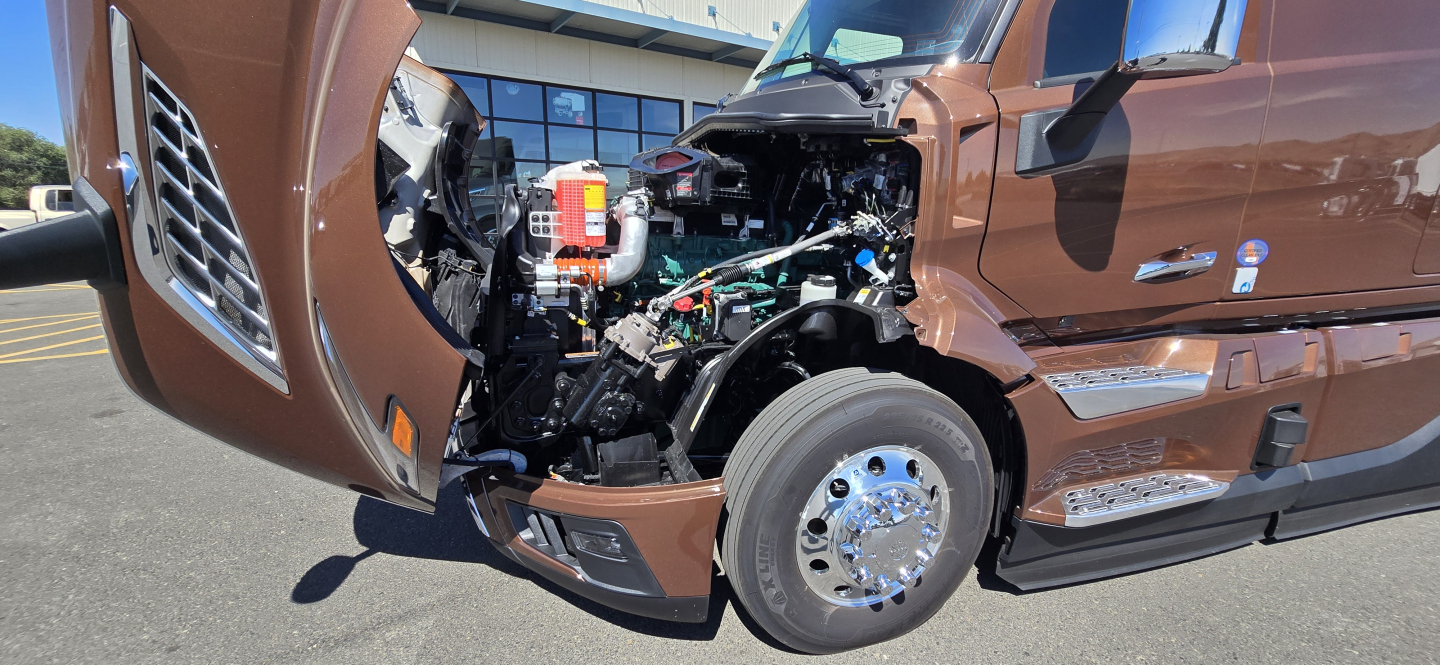 Volvo VNL64T860 cab front with open hood showing engine bay and front wheel.