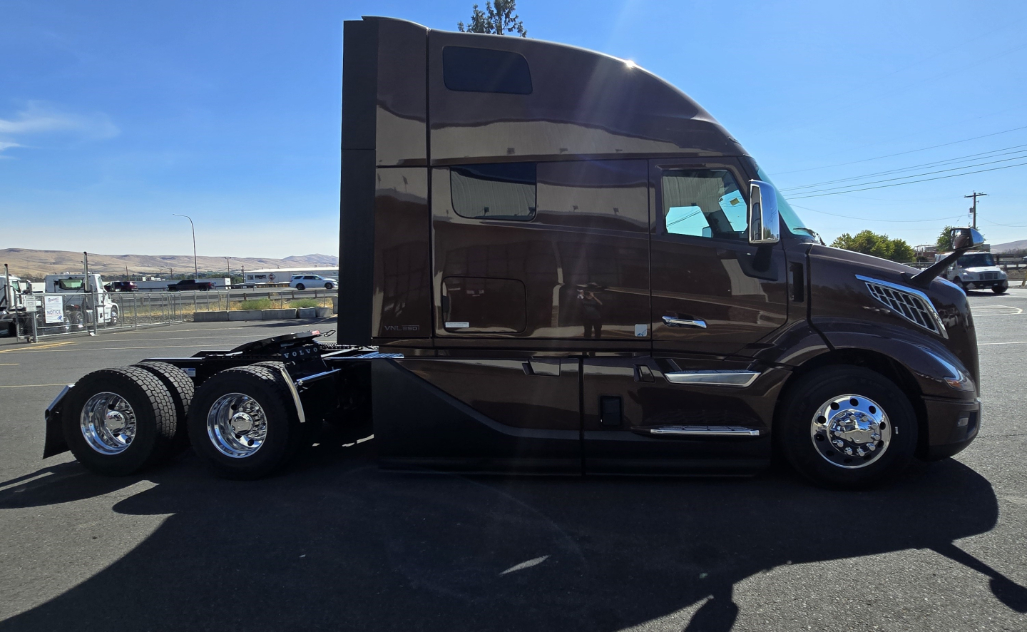 Volvo VNL64T860 tractor trailer side view showing cab with sleeper, dark brown paint, chrome wheels, and dual rear axles.