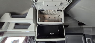 Cab interior View of Volvo VNL under-cab storage compartments with metal brackets and black bin, ceiling area visible.