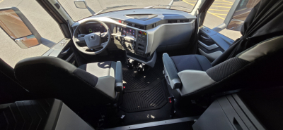Volvo VNL cab interior showing driver's seat, dashboard with steering wheel, and passenger seat in a new conventional sleeper truck.