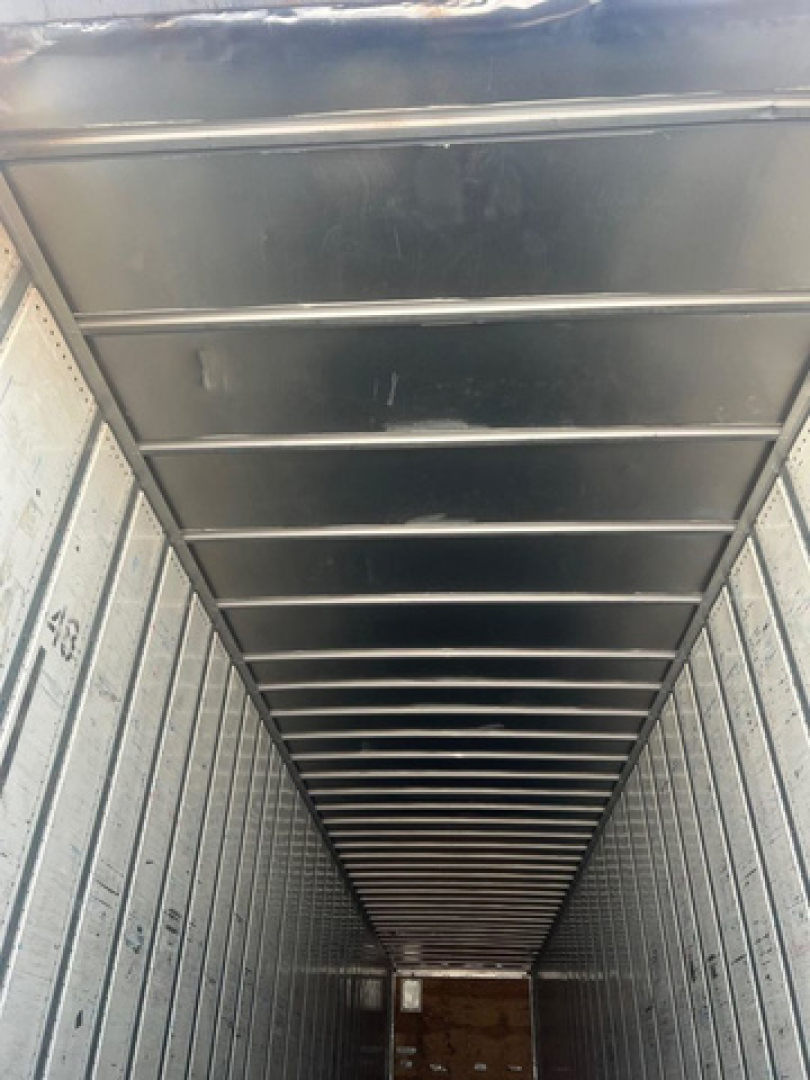 Van trailer interior showing ribbed metal ceiling and sidewalls; empty cargo area with lined walls and open rear.
