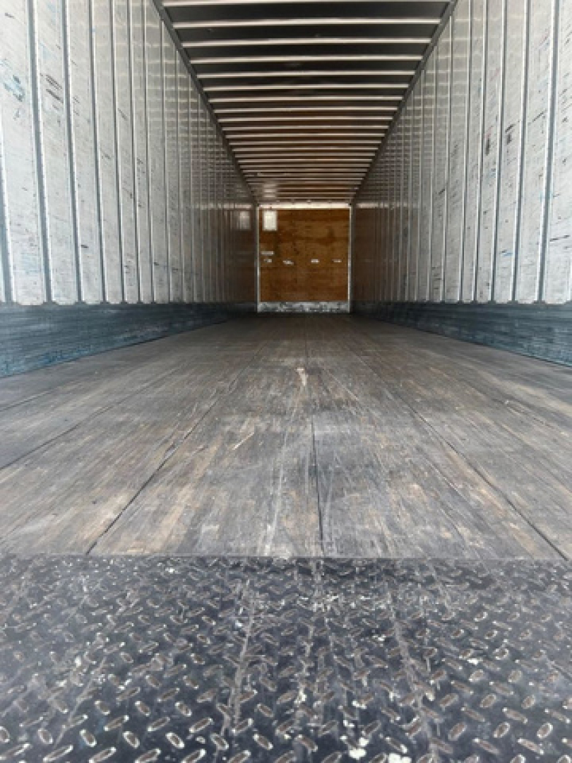Trailer interior showing empty cargo area with wooden interior at far end and metal walls and floor.