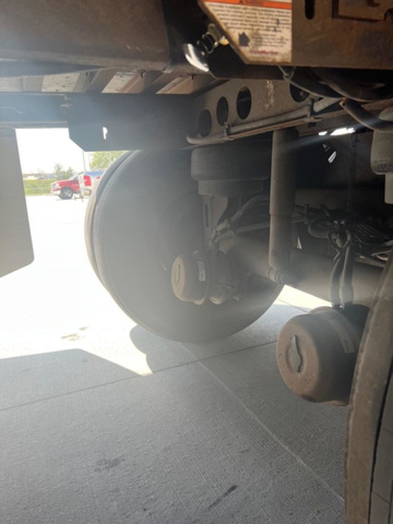 Trailer wheel and undercarriage view showing metallic axle, suspension, and circular wheel hub from a 2012 utility van.