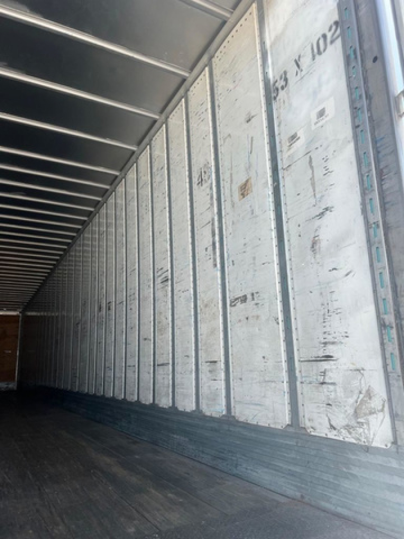 Trailer interior side wall and floor of a used 2012 utility van trailer showing metal wall panels and dark wooden floor.