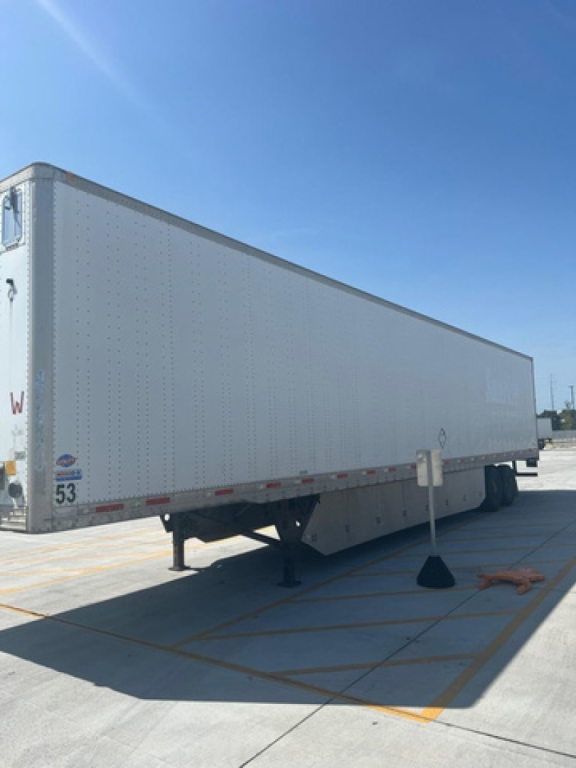 Utility van trailer showing side of white box trailer with some stickers near wheel area and landing gear.