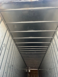 Van trailer interior showing ribbed metal ceiling and sidewalls; empty cargo area with lined walls and open rear.