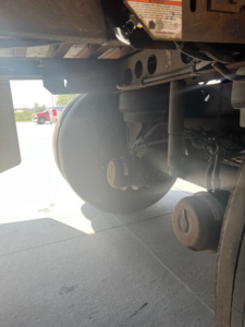 Trailer wheel and undercarriage view showing metallic axle, suspension, and circular wheel hub from a 2012 utility van.