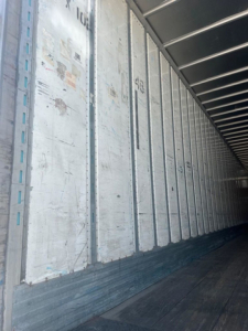 Trailer interior showing metal wall panels and wooden floor indicating cargo area of a used utility van/trailer.