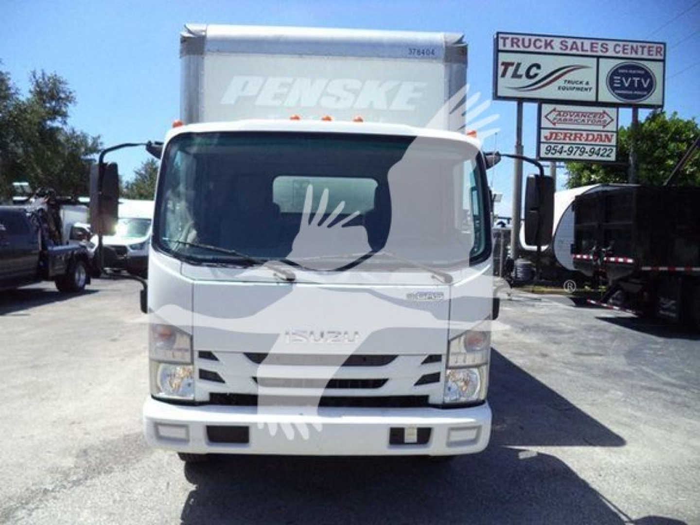 Isuzu NPR HD box truck front view with Penske box in background and dealership sign.