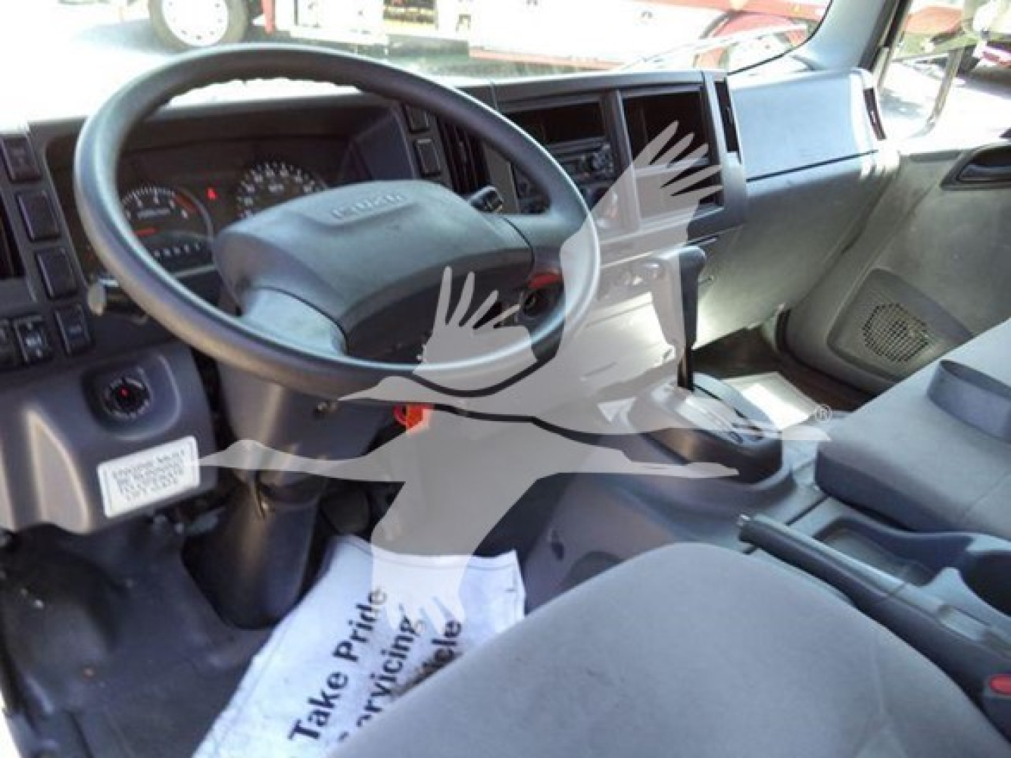 Isuzu NPR-HD truck interior showing steering wheel, dashboard, and center console with driver's seat; dash gauges visible.