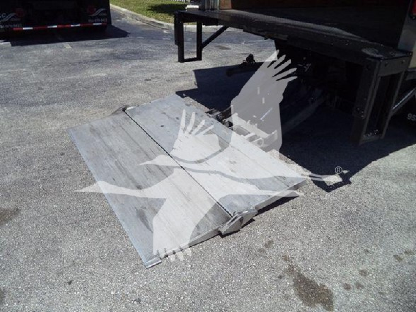Truck bed ramp or platform attached to Isuzu NPR-HD box truck showing metal fold-out ramp supports.