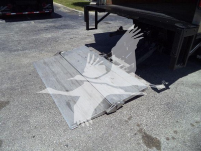 Truck bed ramp or platform attached to Isuzu NPR-HD box truck showing metal fold-out ramp supports.