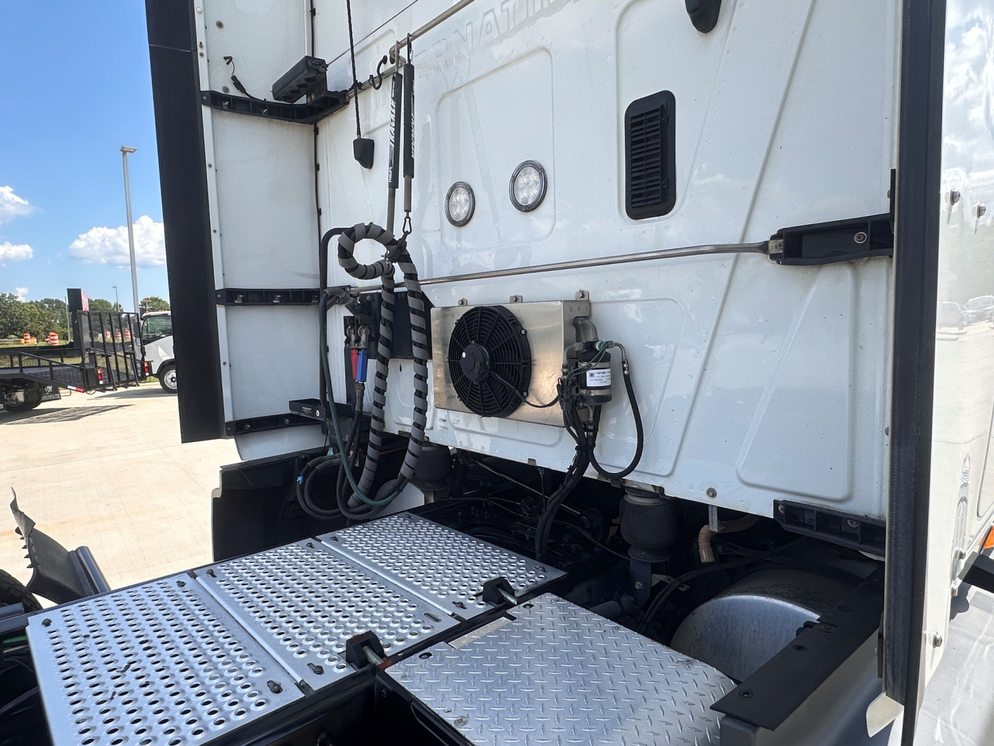 Truck cab rear showing A/C condenser fan and electrical lines on exterior panel of sleeper tractor