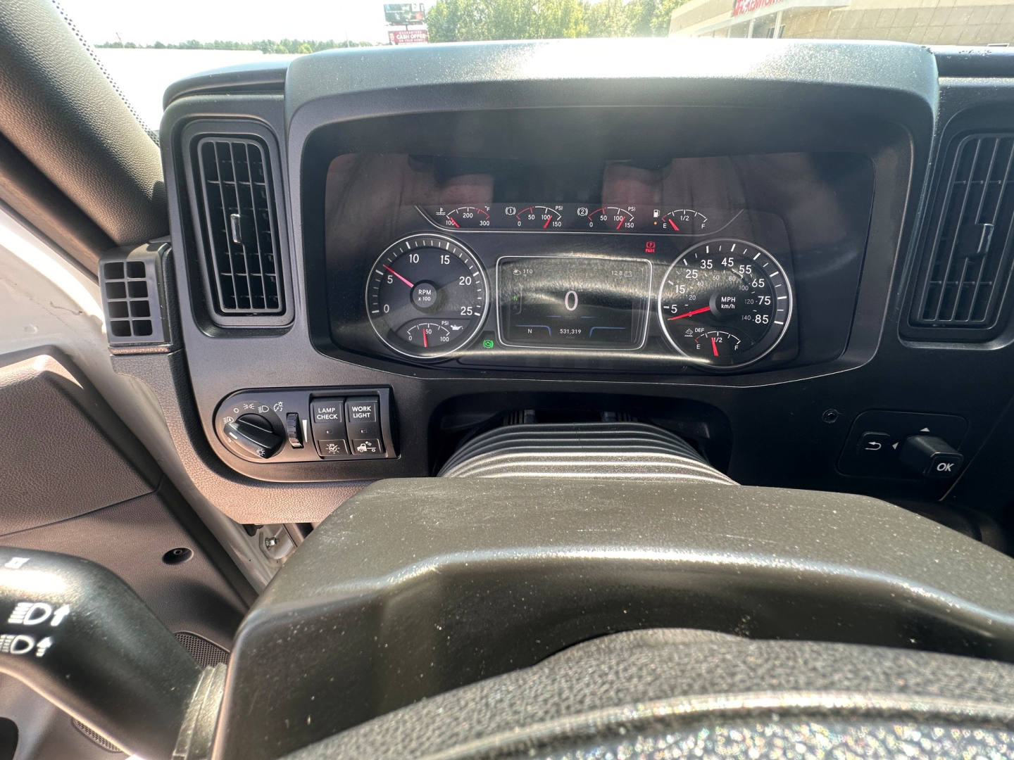 Dashboard of 2021 International LT625 showing instrument cluster with speedometer, tachometer, and digital display in center; steering wheel and control stalks visible.