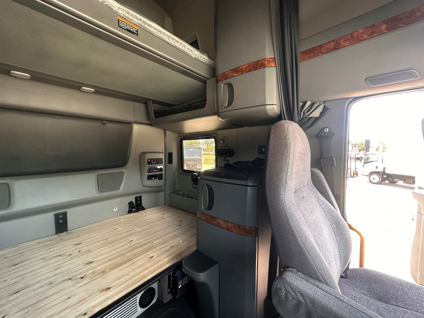Interior sleeper cab of a 2021 International LT625 showing bunk, storage cabinets, and driver seat.