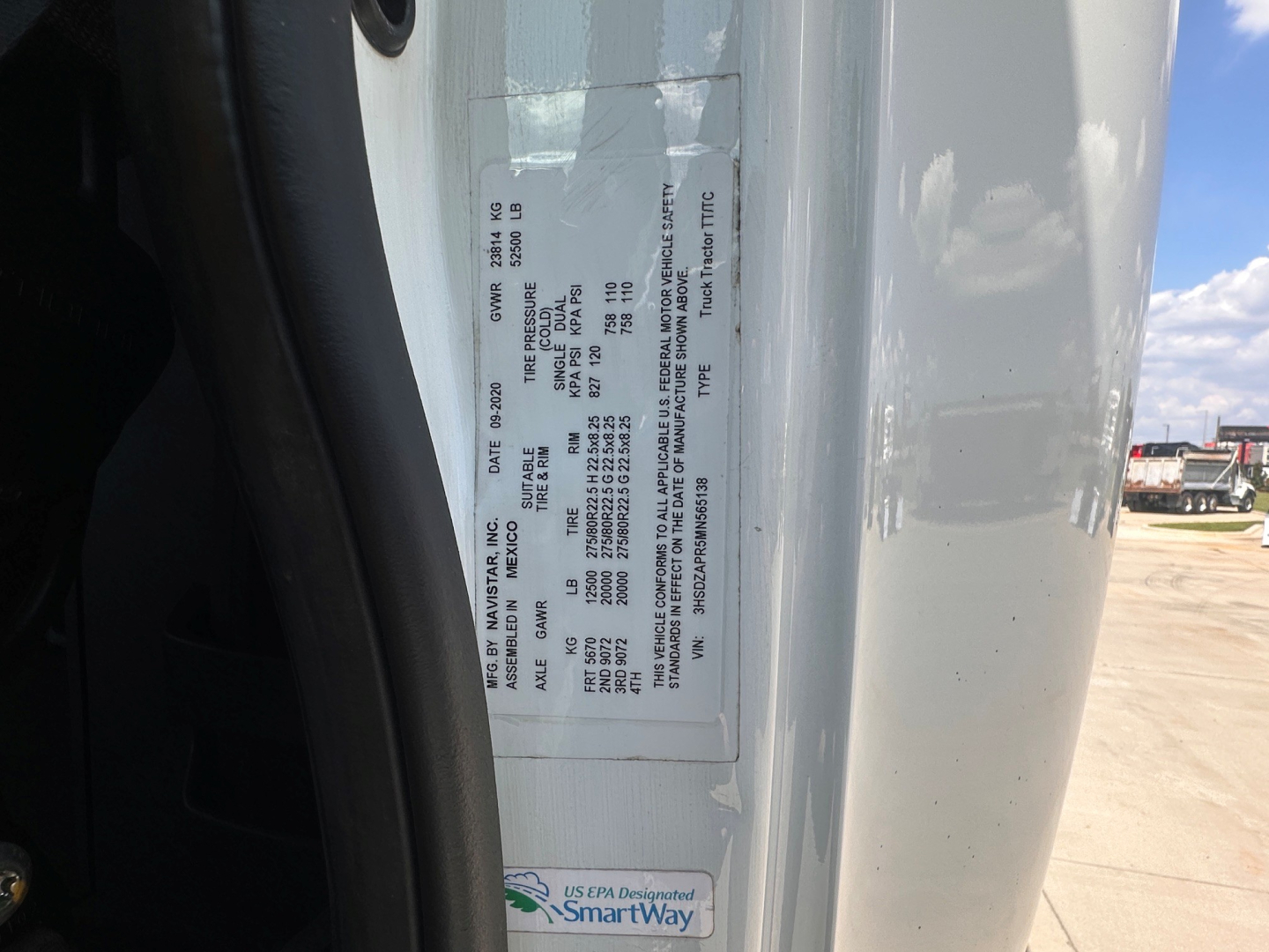 Label on truck door jamb with vehicle VIN and specifications; sticker with small text, part of frame showing a white label and some black printed details.
