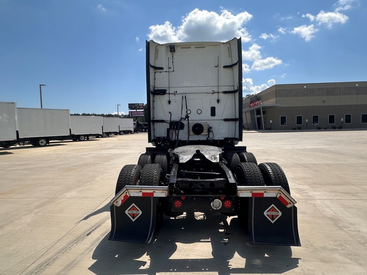 Rear view of a 2021 International LT625 tractor with fifth wheel, dual rear axles, and mudflaps showing hazardous material diamond placards.